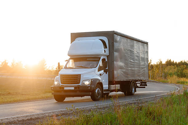 istock truck drives along road at sunset 2224874294