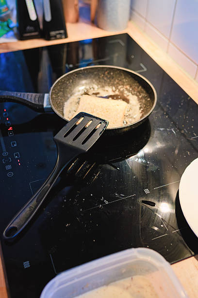 Cooking breakfast on a stovetop with a frying pan and spatula in a modern kitchen setting