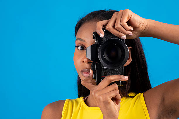 istock Young photographer taking photos with vintage camera on blue background 2224876488