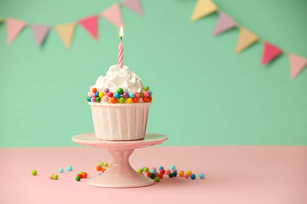 Birthday cupcake with burning candle on pink table. Space for text