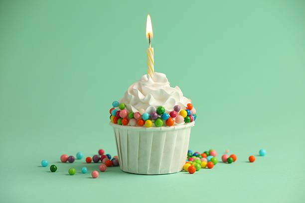 istock Birthday cupcake with burning candle on turquoise background 2224877843