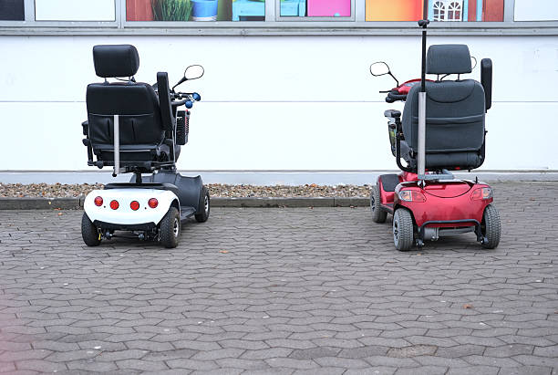 istock Concept aging, overaging, mobility and society in demographic change: Two mobility scooters with shopping basket parked side by side in front of a store 2224877910