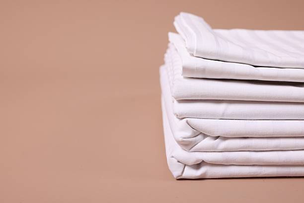 istock Stack of clean bed linens on beige background, closeup. Space for text 2224877953