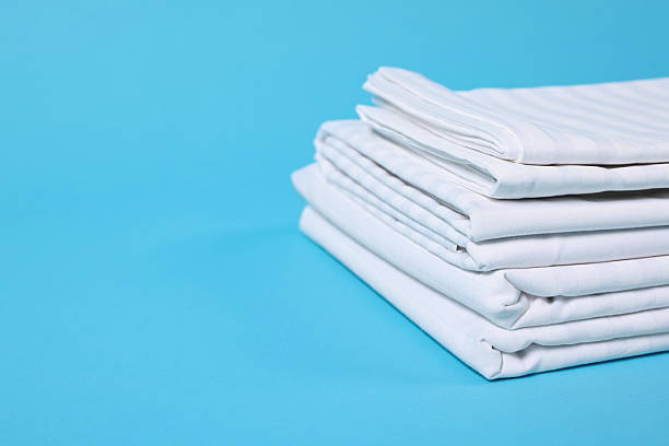 istock Stack of clean bed linens on light blue background, closeup. Space for text 2224877992