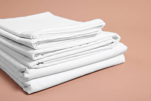istock Stack of clean bed linens on beige background, closeup 2224878004