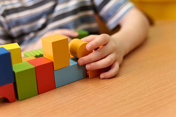 istock A young child is actively engaged in stacking colorful wooden blocks on a table, displaying creativity and focus in a cheerful indoor environment 2224879446