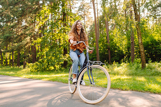 istock Happy woman riding a bicycle in a sunny park. 2224888280