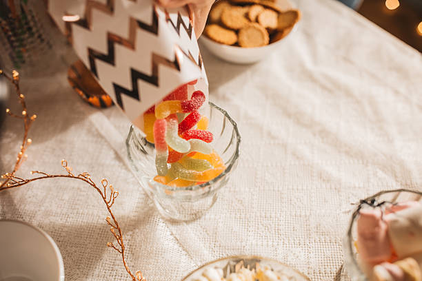 Young woman in costume setting sweet table for Halloween lunch.