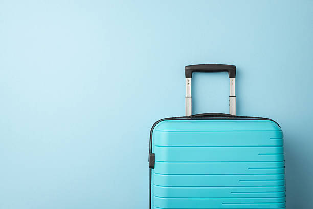 istock A blue hard-shell suitcase positioned in front of a light blue backdrop, evoking travel plans 2224893316