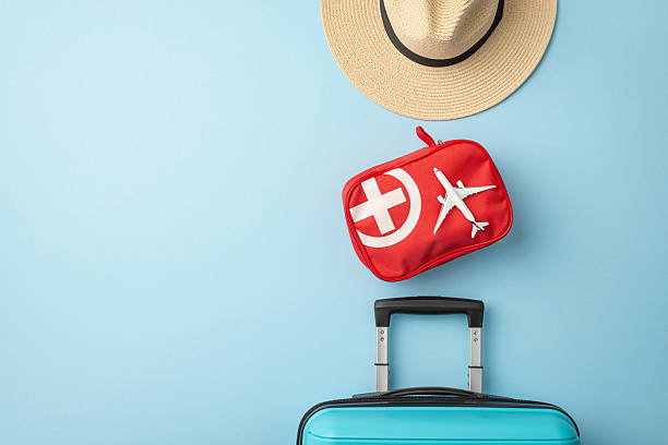 istock Travel essentials including a hat, suitcase, and first aid kit depicted on a blue background 2224893322