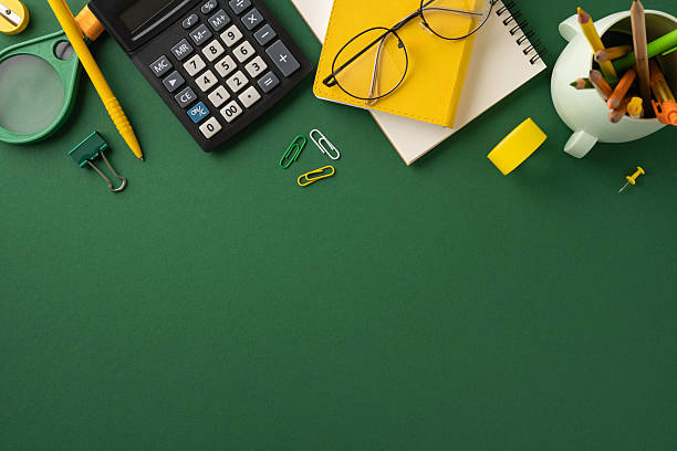 istock School stationery like calculator, notebook, and pens arranged on a green background 2224893347
