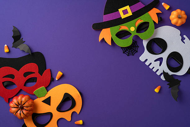 istock Decorative Halloween masks with seasonal elements and candy arranged on a purple background 2224893364