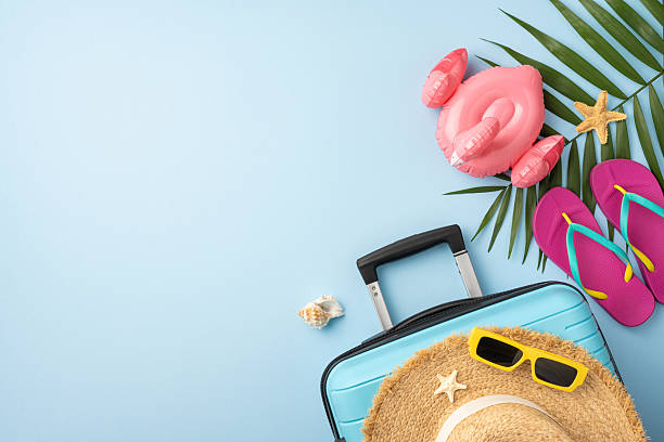 istock Flatlay composition featuring a suitcase, straw hat, sunglasses, and beach items on a light blue background showcasing summer vacation and travel themes 2224893420
