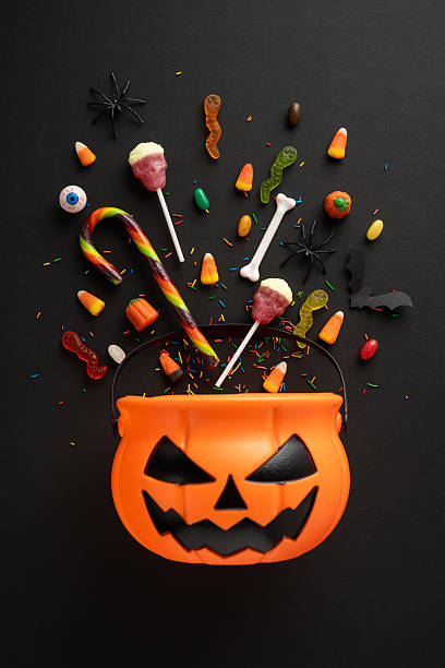 istock Halloween candy and decorations with jack-o-lantern bucket on a dark vertical background enhancing the spooky holiday theme 2224893430