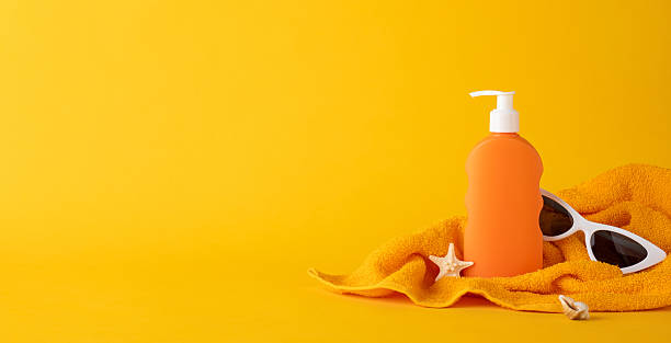istock Sunscreen bottle and towel creating a sun protection concept on a bright yellow backdrop 2224893444