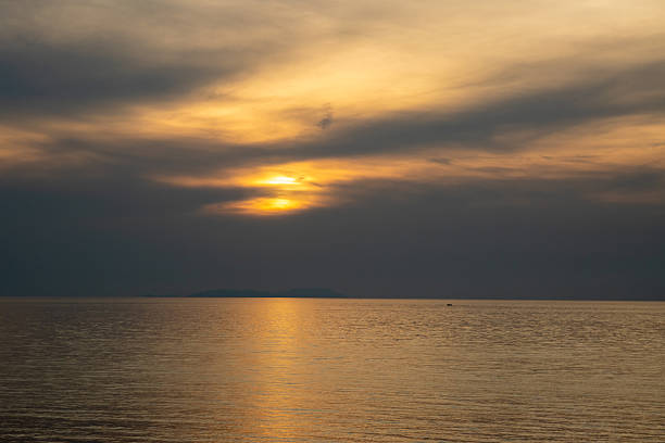 Colorful clouds in the late spring. Cloudy sky and Ionian sea with reflection of the sunlight. Acharavi, Corfu, Greece.