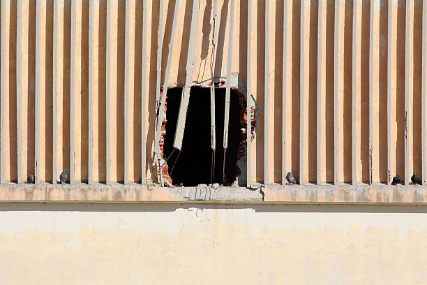 Broken concrete wall with vertical beams and large hole