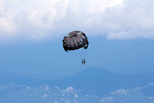 istock Tandem parasailers soaring with black parachute above mountain landscape 2224896288