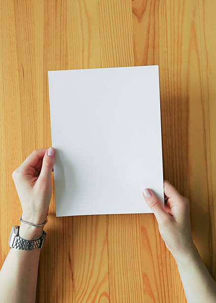 istock Hands Holding a Blank White Paper on a Wooden Surface 2224896952