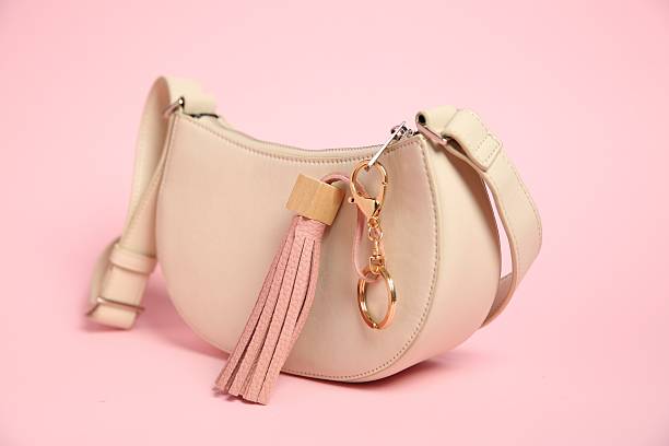 Bag with leather keychain on pink background, closeup
