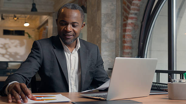 istock African American middle-aged entrepreneur typing laptop computer business man office businessman male guy working with pc online job check data in papers research analyse colourful diagrams documents 2224897900