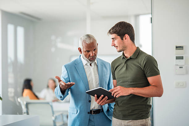 istock Senior Hispanic and Young Caucasian Businessmen Analyzing Data on Tablet 2224909732