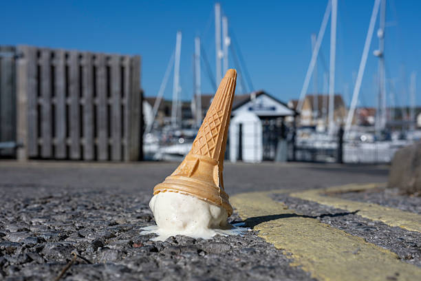 a dropped ice cream cone melting on a sunny road stock photo