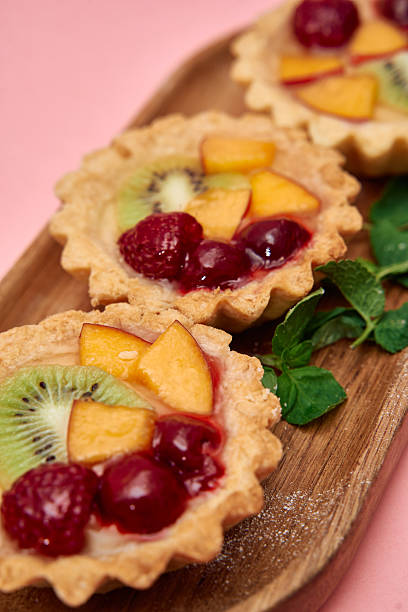Delicious fruit tart trio with mixed berries kiwi peaches on wooden platter