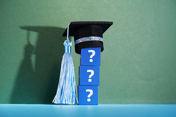 Blue graduation cap, diploma of graduation are arranged on gray surface showcasing academic achievement.