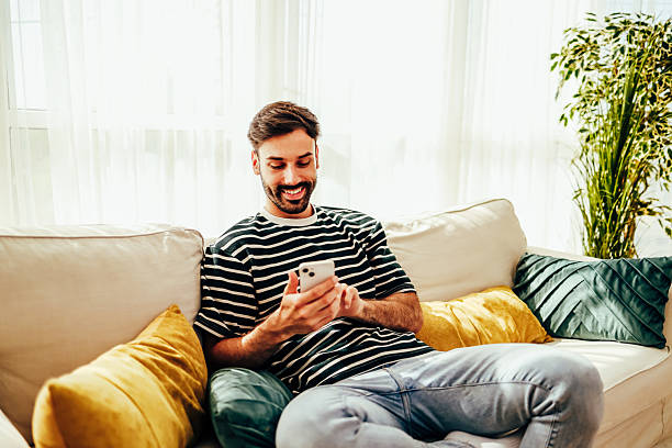 istock Young man relaxing on sofa using smartphone at home 2224933030