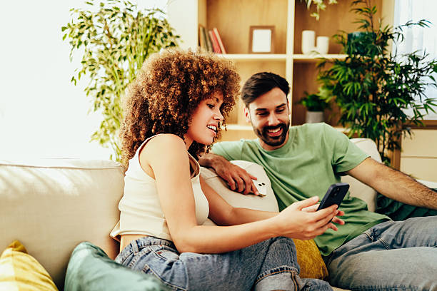 istock Happy couple relaxing on sofa, browsing social media on smartphone 2224935444