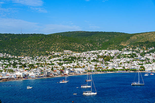 Bodrum, Mugla, Turkey. Many luxury white color yachts, boats anchored at Bodrum city in the middle of blue calm sea. White Bodrum houses in the background.