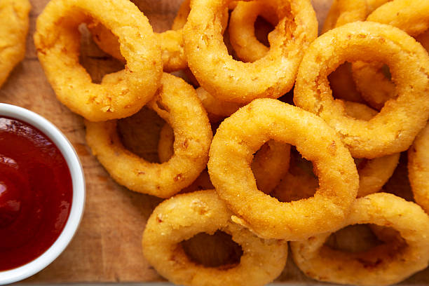 istock Homemade Crispy Deep-Fried Onion Rings with Ketchup on a rustic wooden board, top view. Flat lay. Close-up. 2224942238