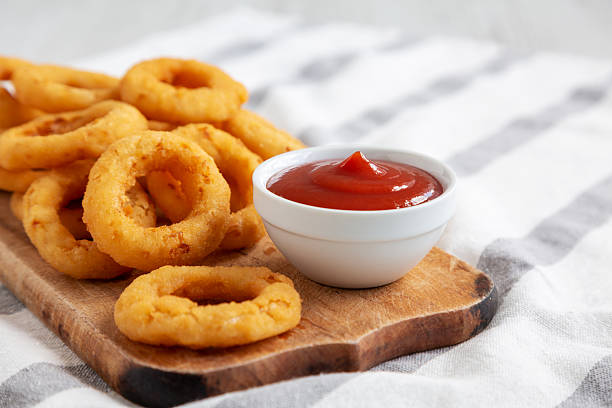 istock Homemade Crispy Deep-Fried Onion Rings with Ketchup on a rustic wooden board, low angle view. Close-up. 2224942523