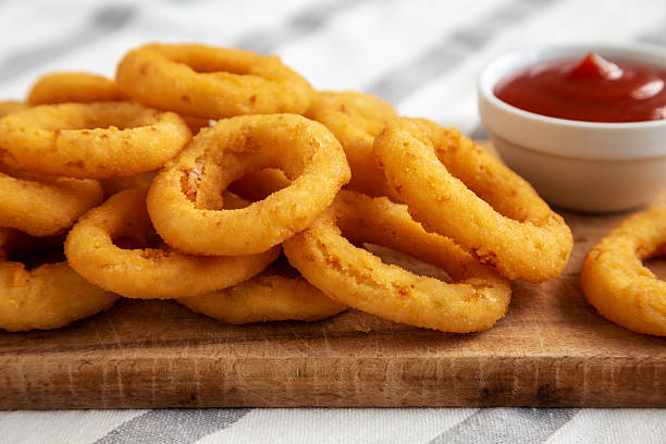 istock Homemade Crispy Deep-Fried Onion Rings with Ketchup on a rustic wooden board, low angle view. Close-up. 2224942541