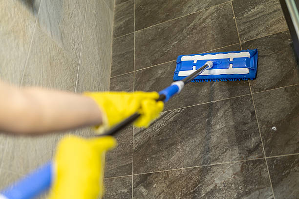 istock Mopping a tiled floor in a modern bathroom with safety gloves during daytime cleaning routine 2224943532
