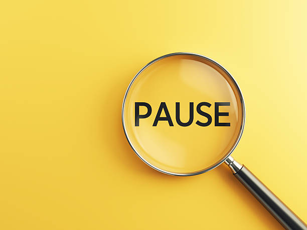 istock PAUSE wording inside of Magnifying glass on an orange background 2224946658