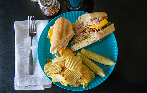 turkey and cheese hoagie with chips and a pickle