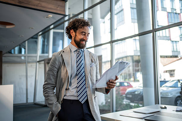 istock Smiling businessman reviewing documents in modern office setting 2224952683