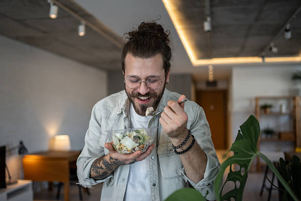 Happy freelancer enjoying a healthy salad during work break at home