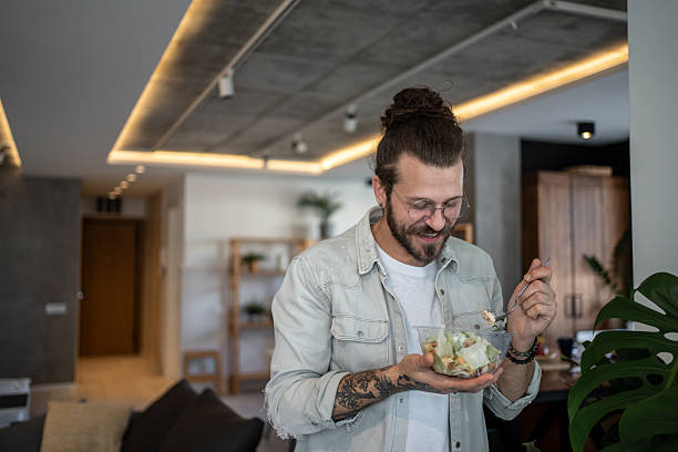 istock Young man enjoying a healthy salad at home 2224954923