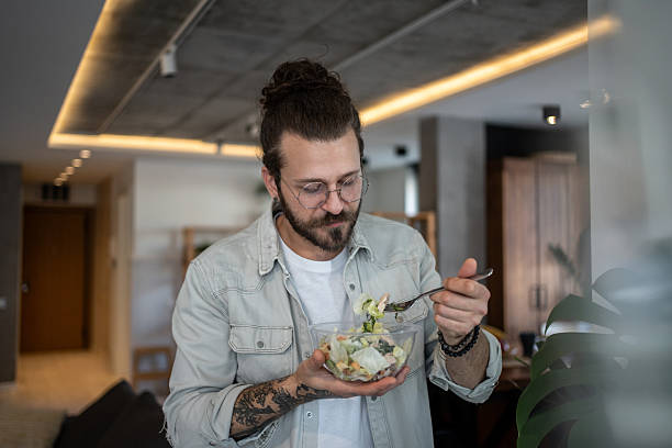 istock Young man enjoying a healthy salad at home 2224954929