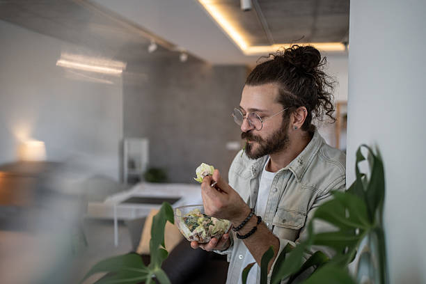 istock Young man enjoying a healthy salad at home 2224954937