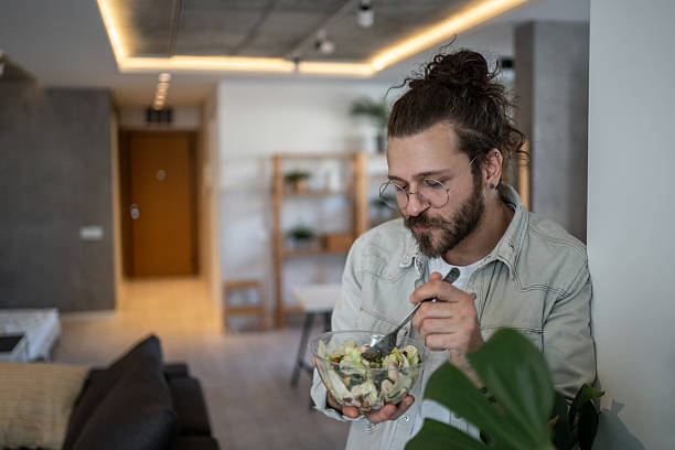 istock Young man enjoying a healthy salad at home 2224954938