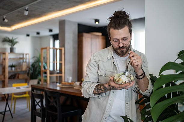 istock Young man enjoying a healthy salad at home 2224954940