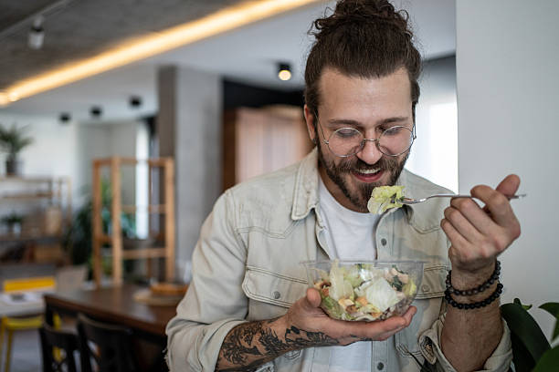 istock Young man enjoying a healthy salad at home 2224954941