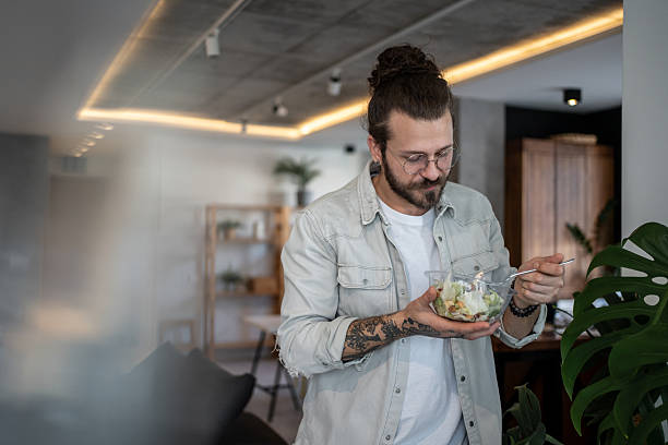 istock Young man eating a healthy salad at home 2224955290