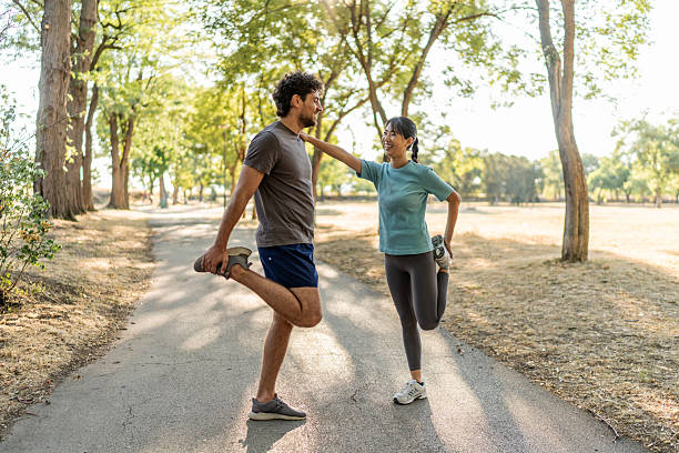 Young couple stretching legs together before running in a park