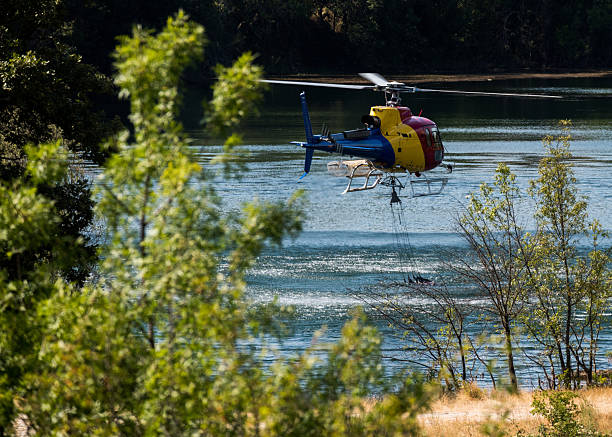 istock Helicopter makes aerial water drop to combat forest fire near serene river 2224962608