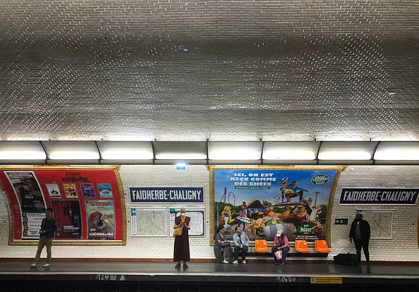 Paris, France - April 5 2025: Passengers waiting for a train at the Faidherbe-Chaligny metro station (11th); one is a monk in a robe.